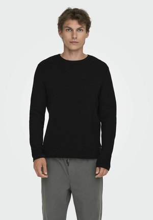 Zwarte langemouwen sweater met een ronde hals, van een geventileerde breimateriaal en een strakke manchetten, gecombineerd met olijfgroene corduroy broek.