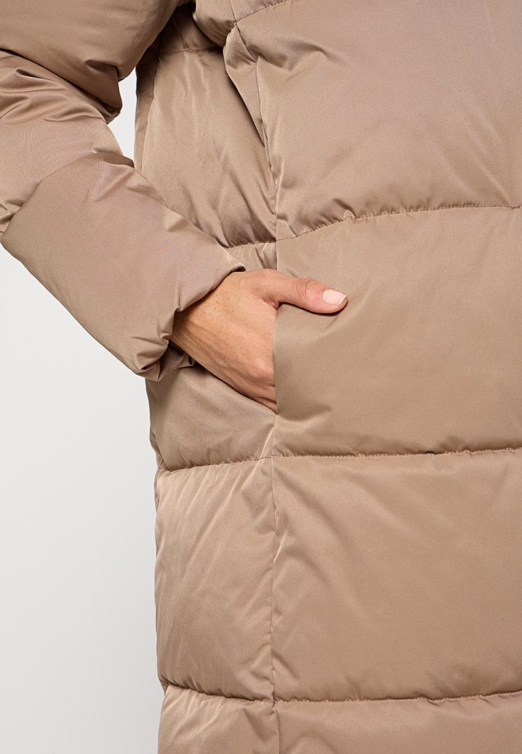 Chaqueta acolchada color marrón claro con un diseño de acolchados, que presenta un bolsillo lateral y una textura suave y brillante en la tela.