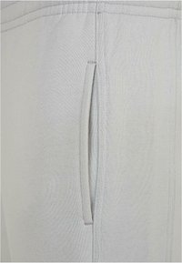 Hellgraue Sweatpants mit Seitentasche, elastischem Bund und strukturiertem Stoff. Die Nähte sind ordentlich verarbeitet für Langlebigkeit.