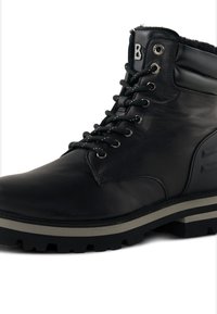 Sorte ankelstøvler i læder med metaløjer, tekstureret overdel, imiteret pelsfor og tyk gummisål med let kile for greb.