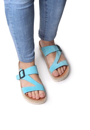 Blå ruskindssandaler med tværgående stropper og justerbar spænde. Vævet jute-platformsål. Båret med lyseblå jeans.