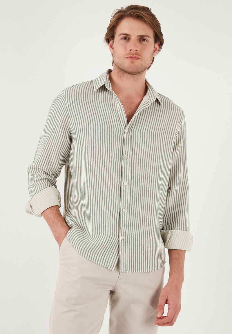 Camisa de manga larga a rayas en verde claro y beige, hecha de tela tejida, con cuello abotonado y mangas remangadas.