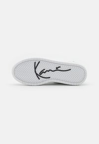 Valge sneakerite tald herringbone mustriga. Omab musta skripti allosas iseloomulikku logo. Tekstuuriga kummikate.