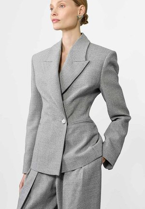 Szary dopasowany żakiet z ostrymi klapami, z jednoprzyciskowym zapięciem i subtelną teksturą, w połączeniu z pasującymi luźnymi spodniami.