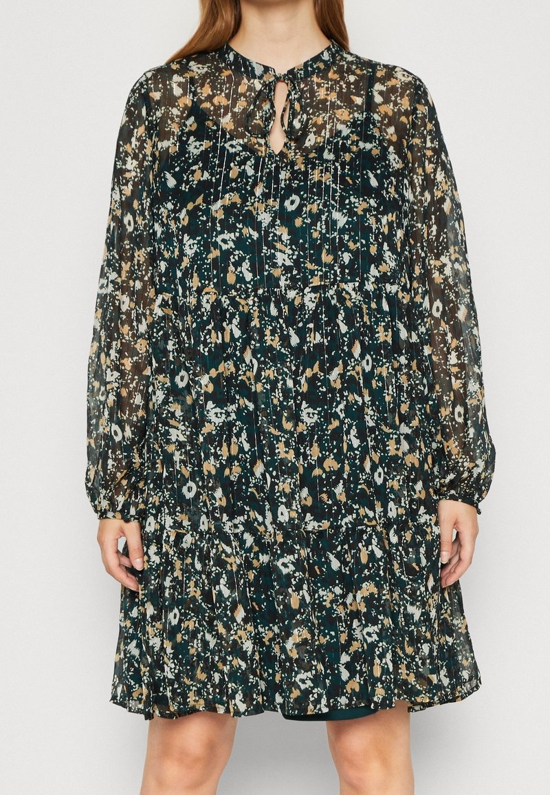 Šaty s květinovým potiskem, průsvitné, tmavě zelené, dlouhými rukávy, s výstřihem ve tvaru klíčové dírky a vrstvou volánů na spodním lemu. Mají světle hnědé a modré akcenty.