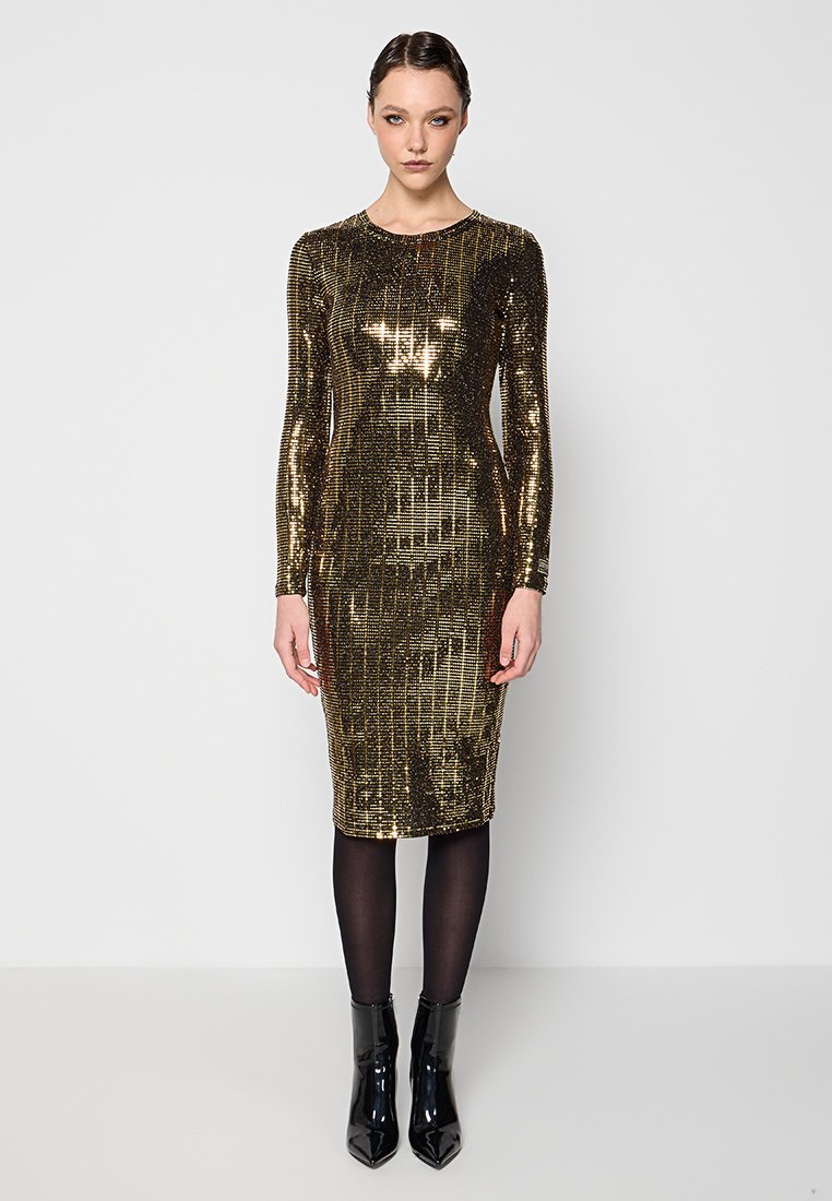 Vestido de lentejuelas doradas con mangas largas, silueta ajustada, dobladillo a la altura de la rodilla, combinado con medias opacas negras y botas de tobillo negras brillantes.