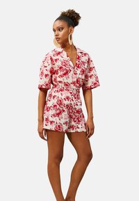 Bodycon floreale con maniche corte e vita con cintura. Presenta uno sfondo bianco con motivi di rose rosse. Realizzato in tessuto leggero.