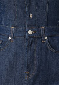 Mørkeblå denimjeans med høy midje, synlige sømmer og metallknapper, med en klassisk fem-lomme-design.