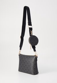 Czarna torba na ramię o teksturowanym wykończeniu, ze złotymi metalowymi elementami i odpinaną okrągłą saszetką na monety z wzorem logo. W zestawie regulowany pasek.