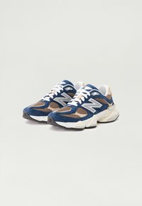 Blue and beige sneakers featuring mesh and suede materials, white laces, large "N" logo, and a thick rubber sole.