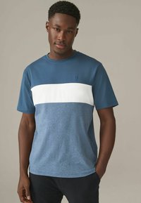 Herret-shirt med et farveblokdesign, der har en mørkeblå overdel, en hvid midtersektion og en meleret blå bund. Lavet af bomuldsmateriale, rund halsudskæring.