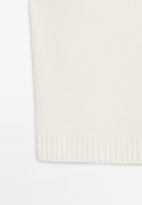 Hvid strikket sweaterstof med en blød tekstur. Ribbet kant nederst skaber en struktureret afslutning. Jævn, ensartet farvning hele vejen igennem.