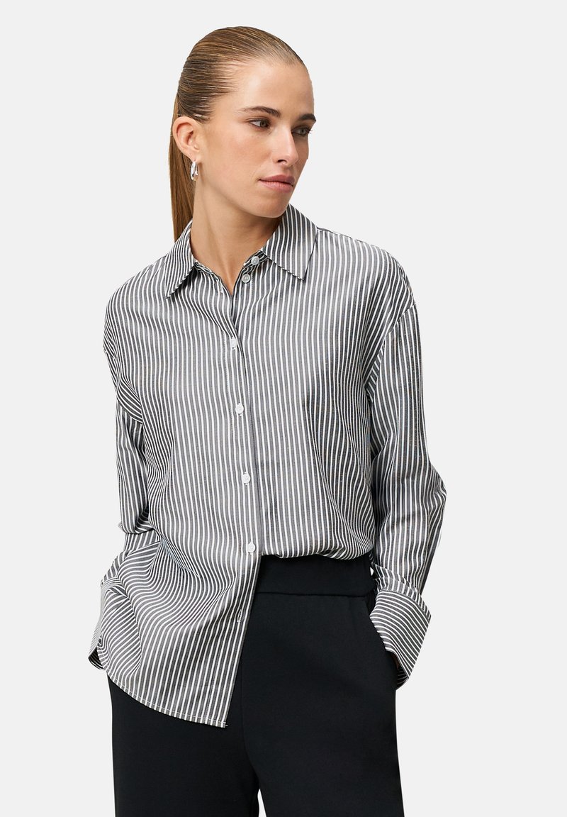 Chemise boutonnée à rayures verticales noires et blanches. Caractérisée par un col classique et des manches longues avec poignets retroussés. Texture de tissu douce.