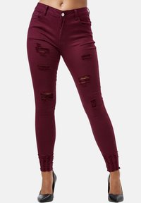Vaqueros skinny burdeos con rotos desgastados, cierre de botón y detalle de dobladillo deshilachado. Tejido elástico para ajuste y comodidad.