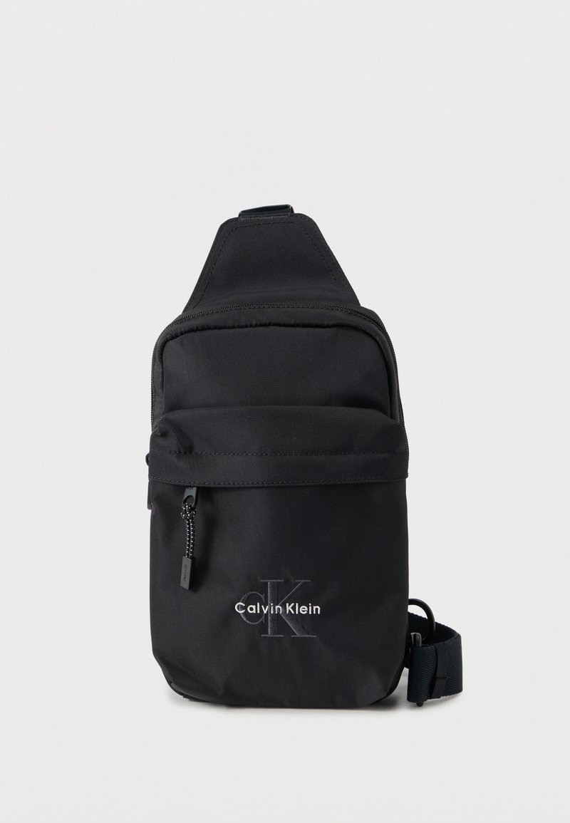 Μαύρο νάιλον τσάντα ώμου με μπροστινή τσέπη με φερμουάρ και ρυθμιζόμενο λουρί. Φέρει το λογότυπο «Calvin Klein» με λευκή κεντητική.