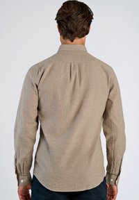 Camicia a maniche lunghe color marrone chiaro realizzata in tessuto testurizzato, con colletto abbottonato e polsini regolabili con bottoni bianchi.