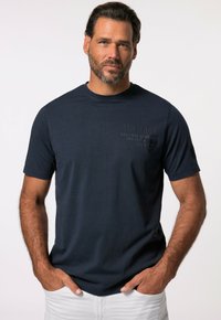 Námorně modré tričko s krátkým rukávem vyrobené z bavlny, s jemným potiskem loga na hrudi a kulatým výstřihem. Měkká textura.