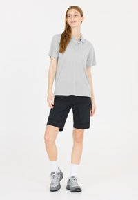 Ljust grå polo skjorta, svarta cargo shorts med fickor, vita ankelsockor och grå vandringsskor. Enkelt, funktionellt design för utomhusbruk.