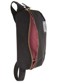 Mustapukuinen kangaspussi, jossa on vetoketjullinen kultainen yksityiskohta. Sisältä punaraitainen ja sivuolkaimi sujuvampaa käsittelyä varten.