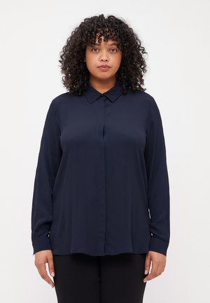 Blusa de manga larga de color azul marino con cuello tipo camisa, cierre delantero de botones y corte holgado. Tejido suave con un ligero brillo y sin patrones.