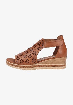 Sandale compensée en cuir marron avec motif floral découpé, bride réglable à la cheville et semelle texturée avec motif décoratif.