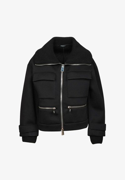 Giubbotto bomber nero con un grande colletto a coste, due tasche sul petto e due tasche frontali con zip. Presenta una chiusura frontale con zip e maniche a coste.