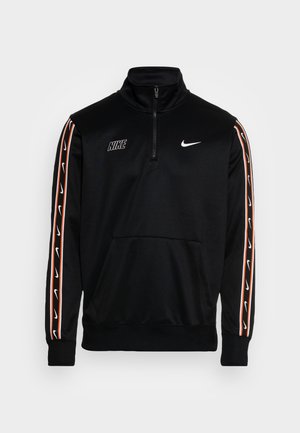 Černý pulovr Nike s čtvrtzipem, bílá loga swoosh na hrudi a rukávech a oranžové pruhy podél paží.