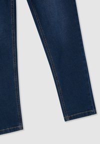 Jeans in denim blu scuro con taglio dritto, dotati di cuciture a contrasto lungo le cuciture e una texture pulita e liscia. Nessun marchio visibile.