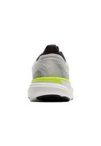 Harmaa ja musta urheilujalkine, jossa on vihreä yksityiskohta kantapäässä, teksturoitu verkko-osa yläosassa ja valkoinen vaimennustyyny, jossa on pyöristetty kärki ja pehmustettu kaulus.