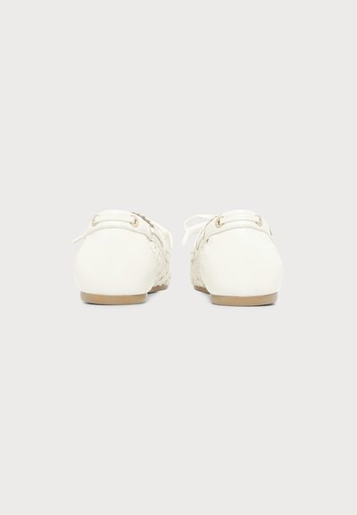 Paire de mocassins en cuir tissé blanc avec semelles plates beige, vue de dos sur un fond gris clair uni.
