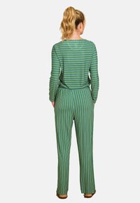 Groen gestreepte lange mouwen top en bijpassende broek. De stof lijkt zacht; beide hebben verticale lijnen in verschillende tinten groen en wit.