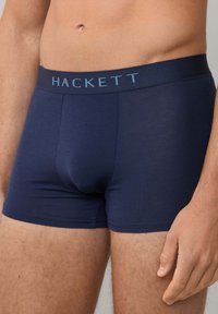 Námornícke modré boxerky vyrobené z hladkej tkaniny so mäkkým pásom, na ktorom je svetlomodré logo značky "HACKETT".