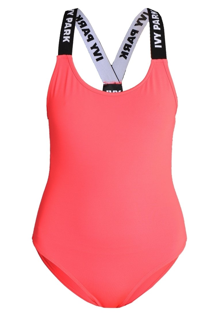 Bright pink one-piece swimsuit with crisscross black straps featuring "IVY PARK" logo. Smooth texture and scooped neckline design.
