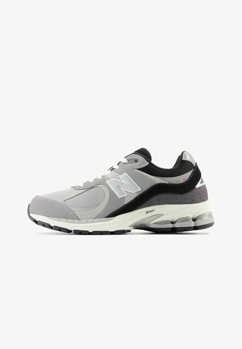 Baskets de sport grises, noires et blanches en mesh et daim, lacets blancs, semelle rembourrée et logo "N" sur le côté.