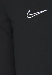 Schwarzer Sportstoff mit glatter Textur; verf�ügt über ein weißes gesticktes Nike-Logo. Unverziertes Design mit minimalen Akzenten.