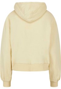 Rövidített, kapucnis pulcsi világos sárga pamutból. Bordás mandzsettákkal és szegéllyel rendelkezik. Simább textúra; elöl nem rendelkezik részlettel. Egyszerű, díszítetlen dizájn.