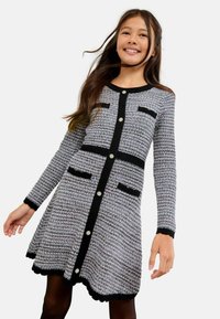Sukienka z długim rękawem z plecionego szarego materiału z czarnymi akcentami, z okrągłym dekoltem, zapięciem na guziki i falbaniastym dołem. Zawiera kieszenie.