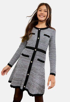 Langärmliges Kleid aus einem gewebten grauen Stoff mit schwarzen Akzenten, Rundhalsausschnitt, Knopfverschluss und gewelltem Saum. Mit Taschen.