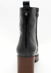 Bottines en cuir noir avec une finition texturée, une fermeture éclair latérale et un talon bloc en bois marron. Présente un accent logo en métal en haut.