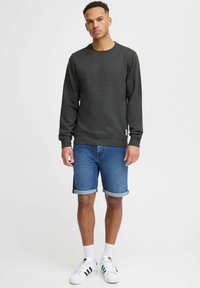 Gray long-sleeve sweatshirt, denim shorts, white socks, and black-striped sneakers. Simple, textured fabric with ribbed cuffs and hem.