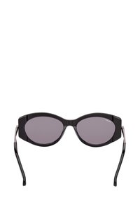 Černé oválné sluneční brýle s tlustými rámy a tmavými skleněmi, zobrazené zepředu na bílém pozadí.