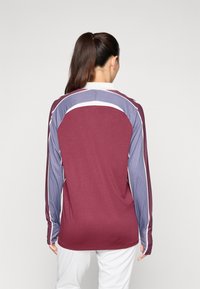 Langærmet skjorte med en maroon farve og blå og hvide stribede detaljer på ærmerne, fremstillet af tekstureret stof med en afslappet pasform.