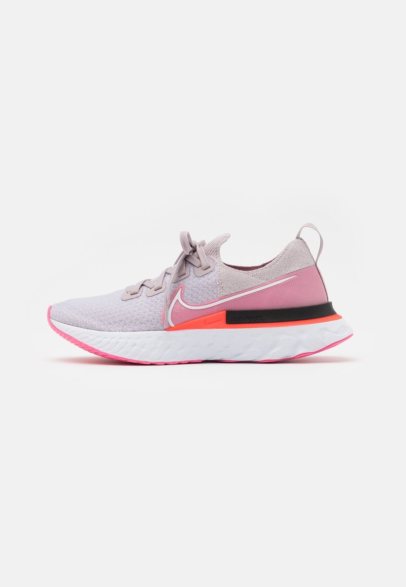 Chaussures de sport avec une tige en maille violet clair, des accents roses au talon, une semelle intermédiaire noire et une semelle extérieure blanche texturée avec des détails roses.