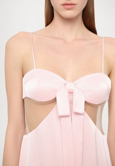 Vestido de satén rosa con detalle de lazo en el busto, tirantes finos y paneles laterales transparentes, con una textura suave y un diseño fluido.