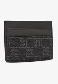 Svart kortinnehavare med en texturerad tyg som har ett rutmönster och präglade siffror, kompletterad med släta läderdetaljer.