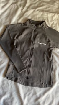 Pilkas sportinis džemperis su aukšta apykakle, pilnu priekių užtrauktuku ir sustiprintomis siūlėmis. Yra baltas "PEGADOR" logotipas priekyje.