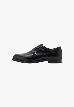 Scarpe doppie monk in pelle nera con punta arrotondata e fibbie argentate. La texture liscia e il tacco piatto offrono stabilità.