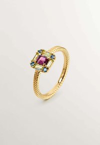 Anillo de oro con una banda texturizada, con una gema central púrpura rodeada de acentos verdes y azules, en un diseño rectangular.