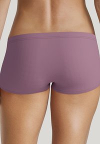 Lila Badehose mit glattem, elastischem Material. Einfaches Design mit niedrigem Schnitt und geraden Nähten für zusätzlichen Komfort.