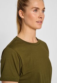 Olivengrøn bomulds t-shirt med rund hals og korte ærmer, der har en glat tekstur og en tætsiddende design. Enkel og alsidig stil.